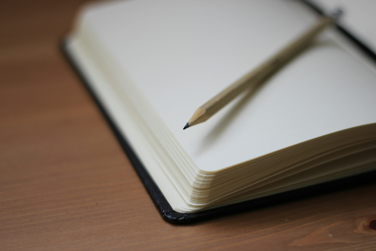 An open notebook with a pencil on a desk